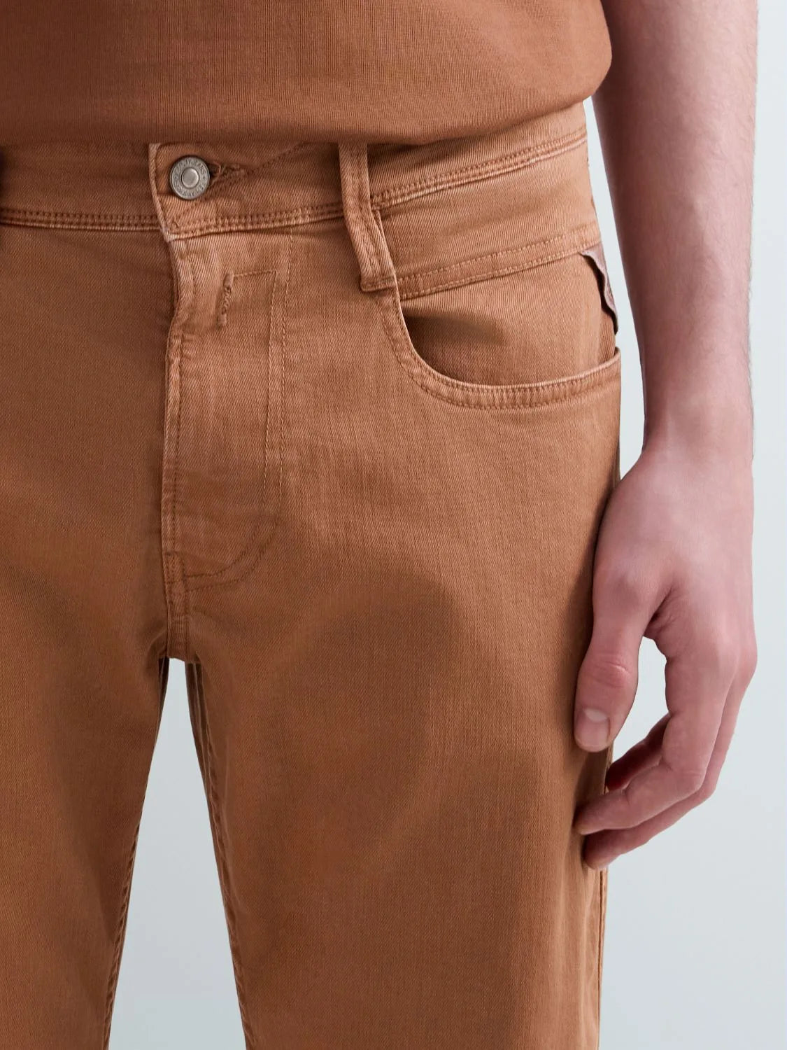 Replay M914Y Anbass slim-fit men's jeans in tobacco color, shown hanging with front pockets and classic denim texture.