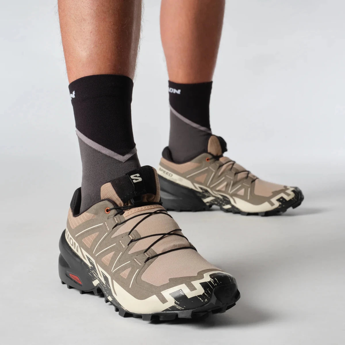 Men's Salomon Speedcross 6 sneakers in natural, black, and almond milk with rugged trail running design.